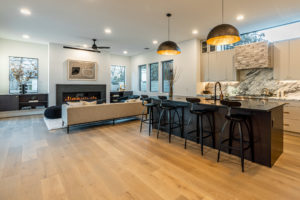 Open plan kitchen and living room with custom soapstone gas fireplace at 2007 De Verne custom home
