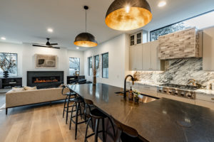 Open plan kitchen and living room with custom soapstone gas fireplace at Zilker custom home